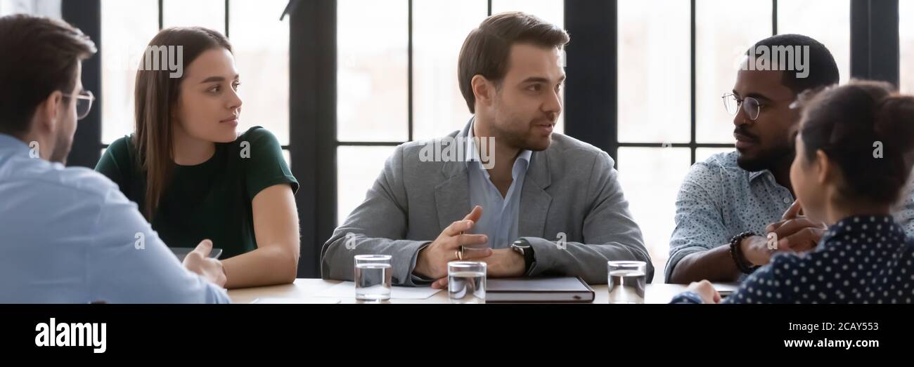 Ampia immagine di un uomo d'affari sicuro che parla, condividendo opinioni in occasione di una riunione aziendale Foto Stock