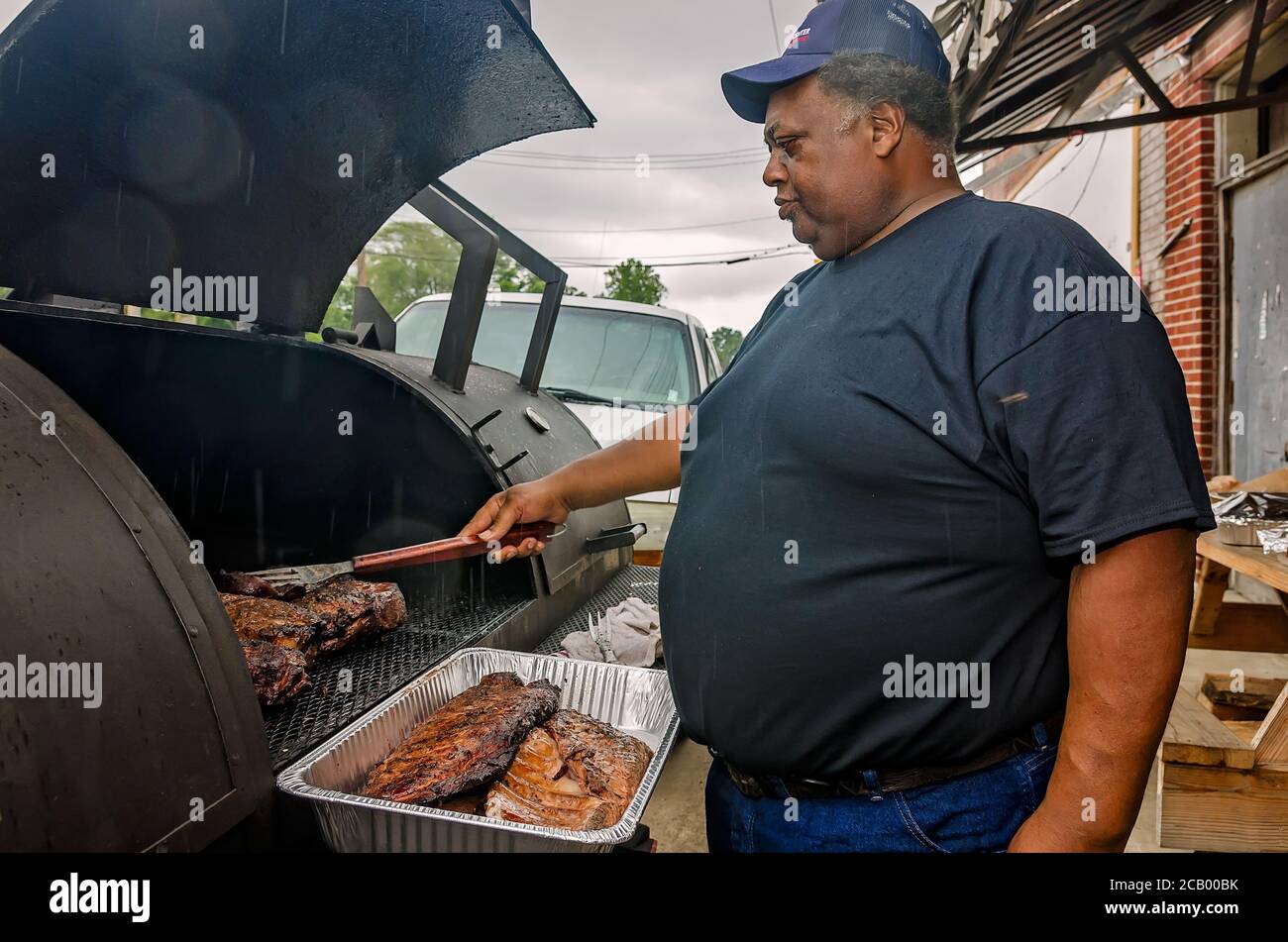 Un uomo barbecue sotto la pioggia al di fuori del Red’s Blues Club durante il Sunflower Blues and Gospel Festival di Clarksdale, Mississippi. Foto Stock
