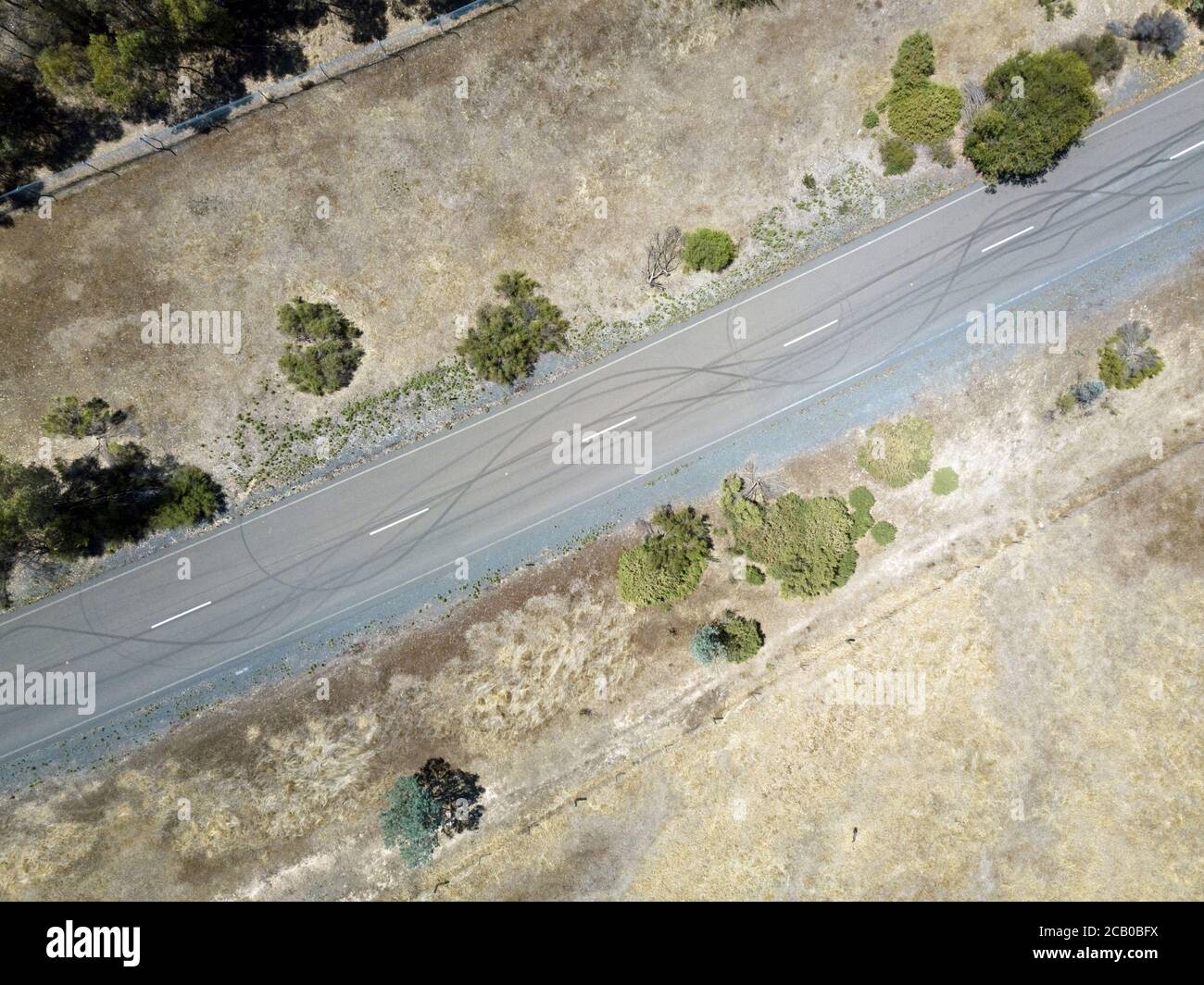 Auto skid Mark vista aerea su strada asfaltata con campi d'erba e recinzione, Victoria, Australia. Foto Stock