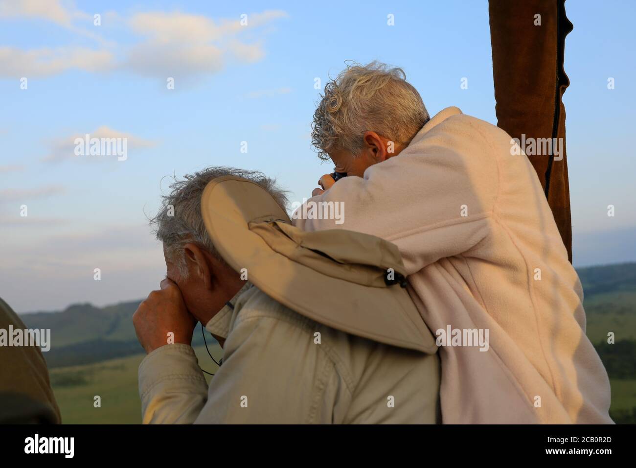 Una coppia più anziana gode di un giro panoramico in mongolfiera sulla savana africana durante un safari, ammirando splendide viste panoramiche. Foto Stock