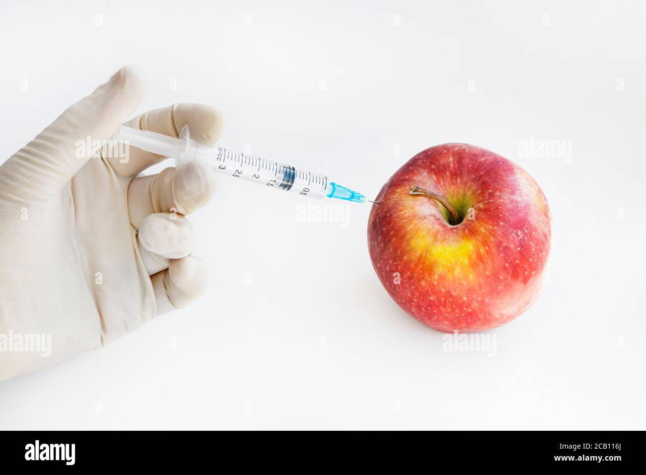 Iniezione nella mela rossa - frutta geneticamente modificata e siringa con sostanza chimica rossa. Alimenti OGM. Ricerca di laboratorio, selezione di frutta. Modif. Geneticamente Foto Stock