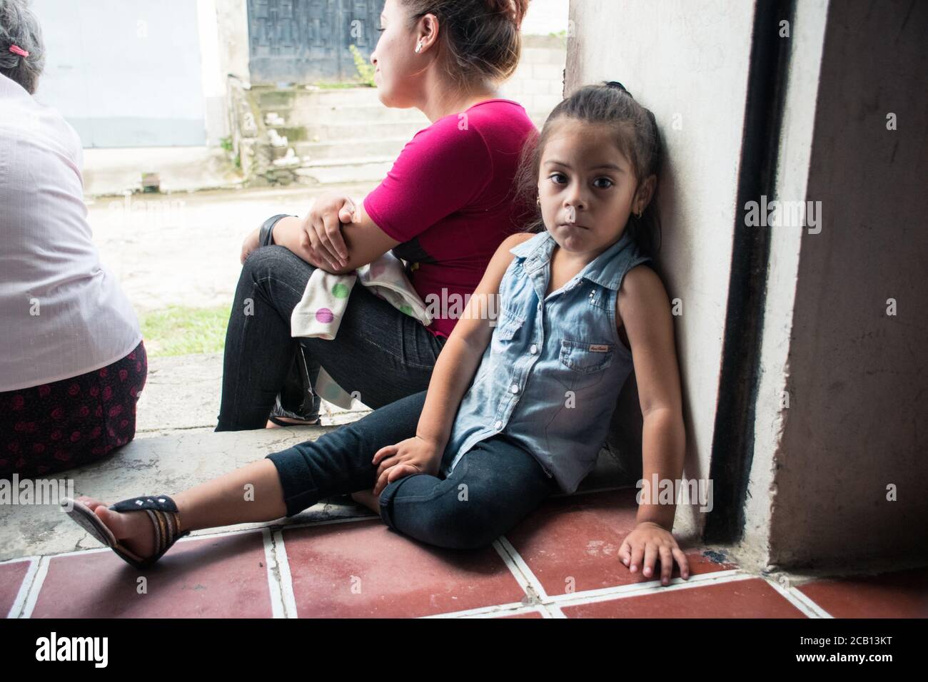 Citala / El Salvador - 20 ottobre 2017: Ritratto di bambina in attesa dell'autobus con la madre seduta sul gradino Foto Stock