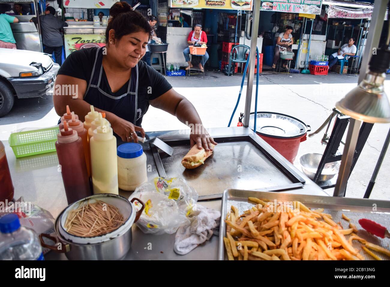 Santa Ana / El Salvador - 28 ottobre 2017: Salvadoran donna preparare sandwich al chiosco cibo di strada Foto Stock