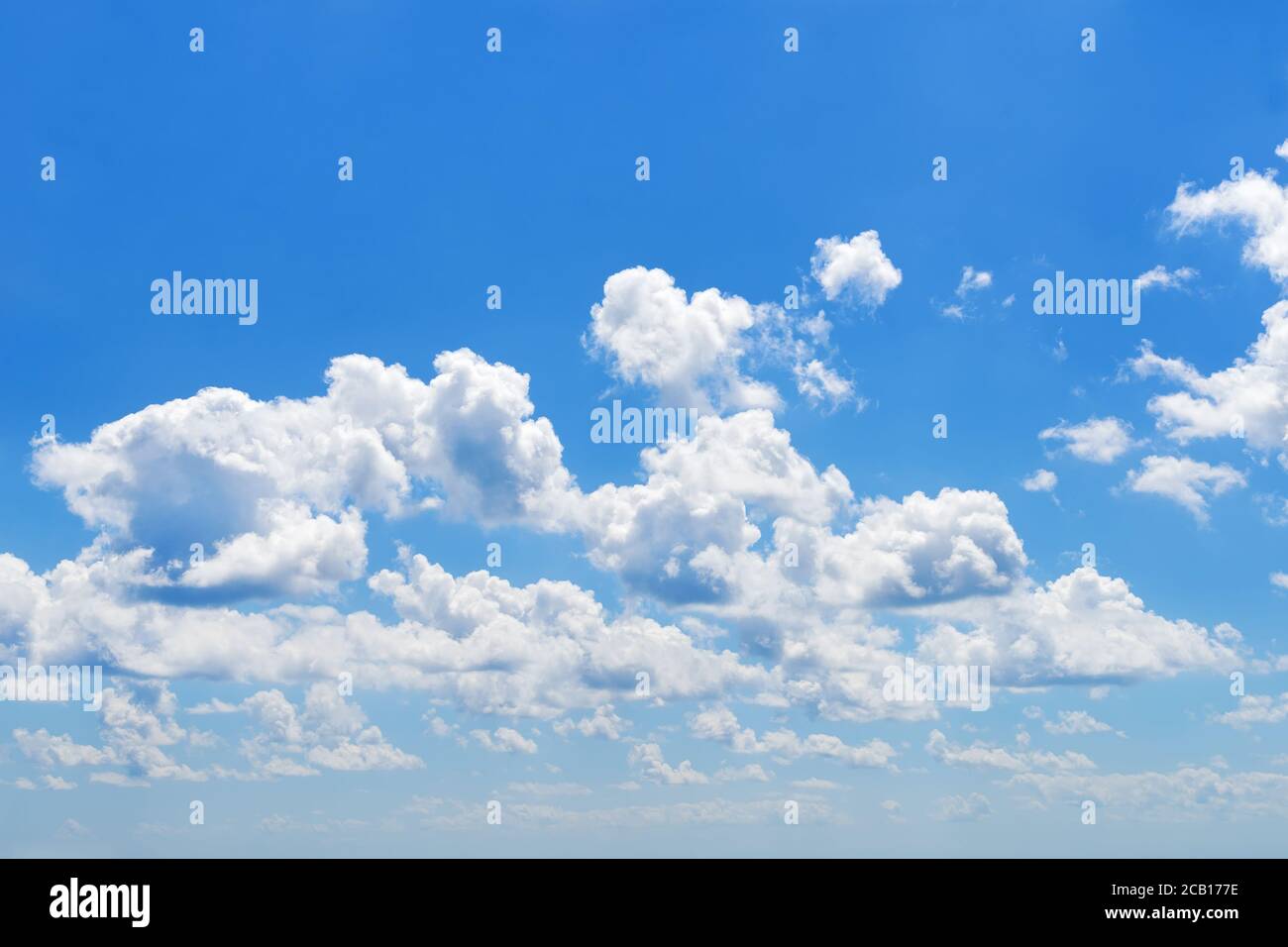 Piccole nuvole bianche soffici galleggiano piacevolmente in alto nel cielo estivo blu luminoso in un giorno. Bel tempo soleggiato, vacanze al mare e vacanze estive. Foto Stock