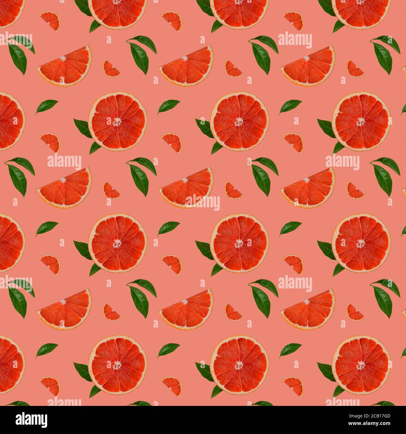 Motivo senza cuciture di semi di pompelmo rosa, fetta e foglie su uno sfondo rosa corallo. Frutta fresca modello estivo. Giacitura piatta isometrica. Vista dall'alto. Foto Stock