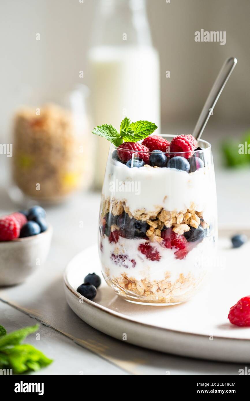 Bicchiere di parfait di granola, frutti di bosco e yogurt sul tavolo. Inquadratura ad angolo, vista ravvicinata, messa a fuoco selettiva. Foto Stock