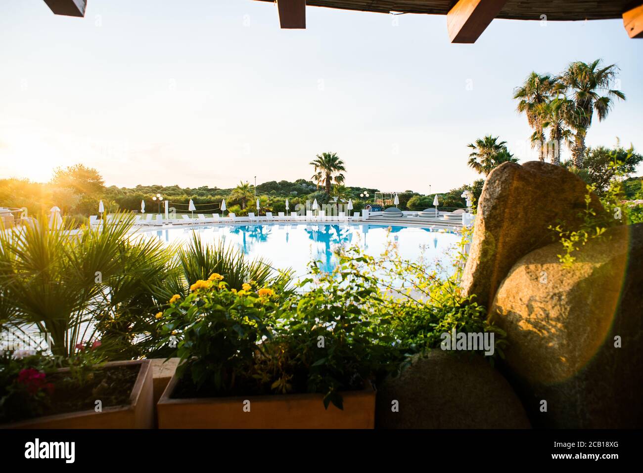 Piscina d'acqua con lettini, ombrelloni e Palme. Vista panoramica di lusso. Sardegna. Italia. Alba. Foto Stock