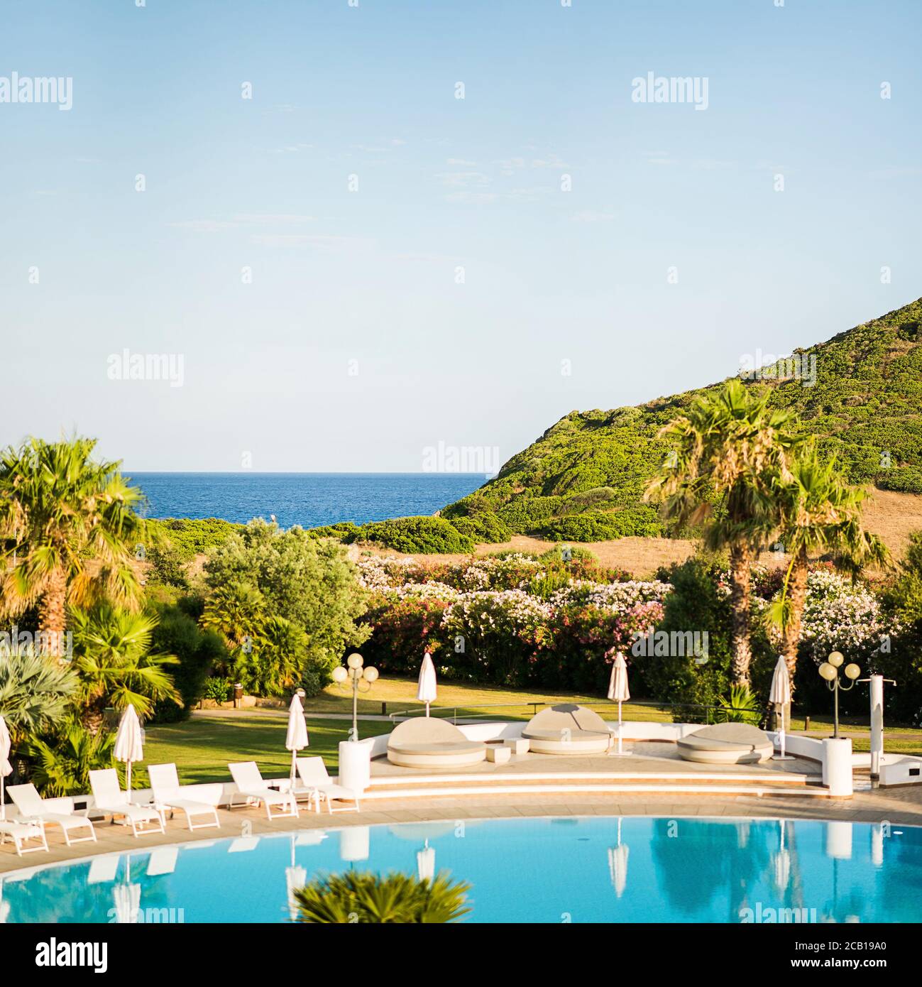 Piscina ad acqua vuota con lettini e ombrelloni. Paesaggio mediterraneo. Lussuosa vista panoramica sul Mar Mediterraneo. Sardegna. Italia. Foto Stock