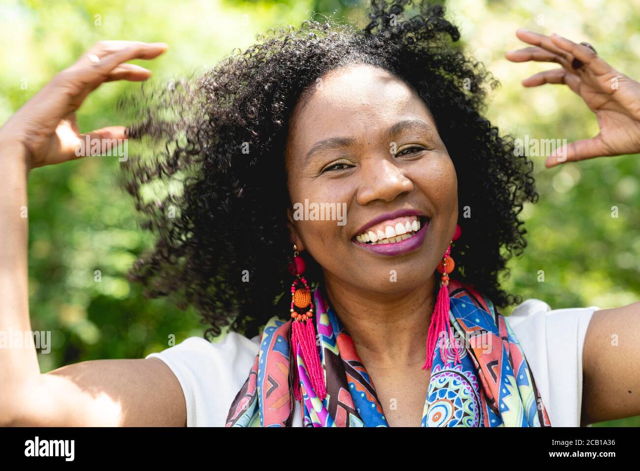 Ritratto di una donna ridente, dalla pelle scura con capelli ricci e sciarpa colorata, Germania Foto Stock