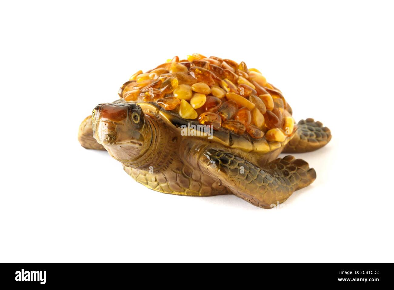 Figura di una tartaruga su sfondo bianco con pietre ambra sulla conchiglia. Foto Stock