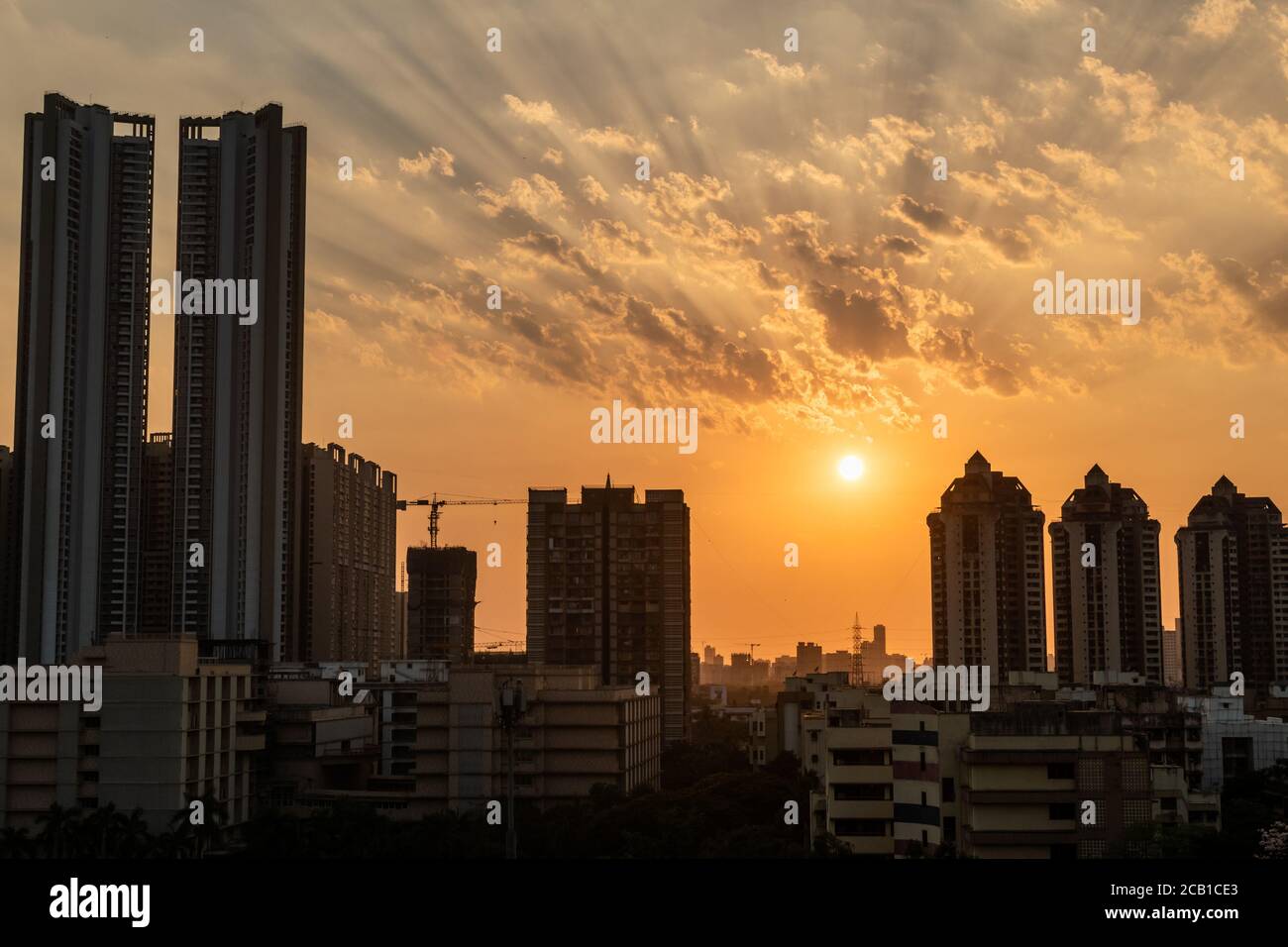 Mumbai, Maharashtra, India - Marzo 2020: I raggi del sole che si stagliano attraverso le nuvole dietro gli alti grattacieli del sobborgo di Kandivali nella città di M. Foto Stock