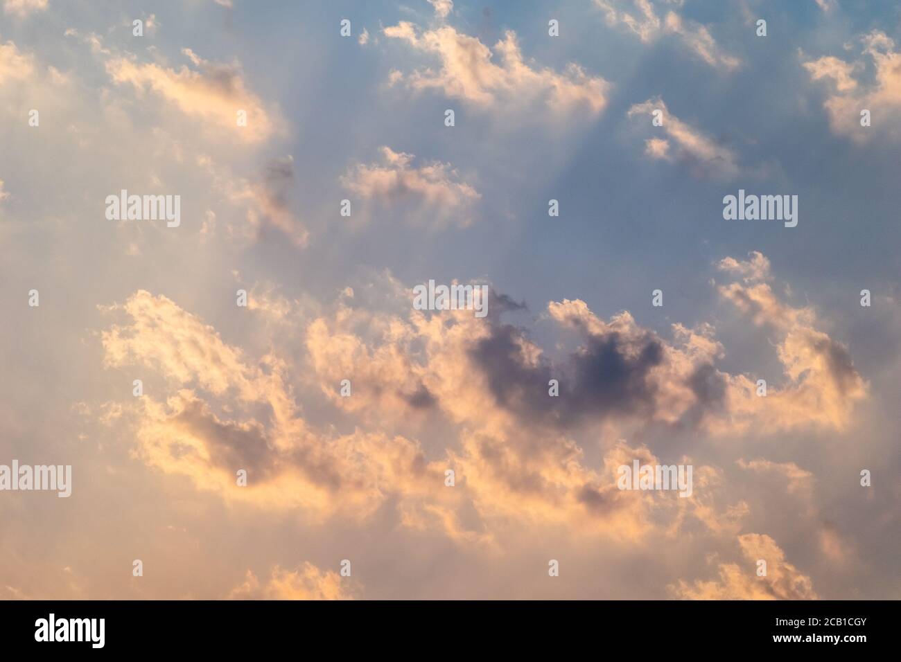 Il sole si infrange attraverso le nuvole in un cielo blu Foto Stock