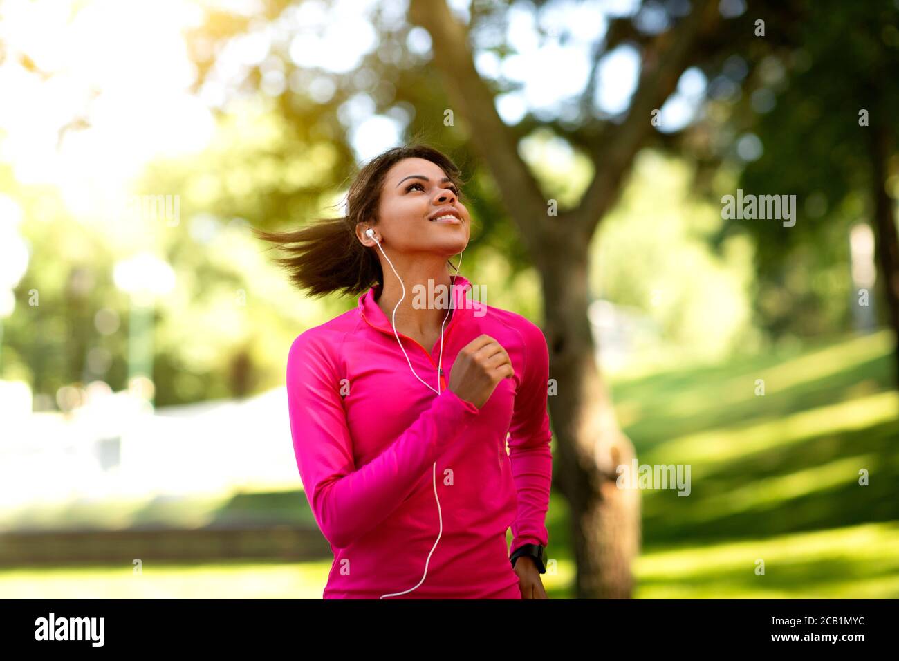 Gioiosa ragazza nera che fa jogging nel parco estivo Foto Stock