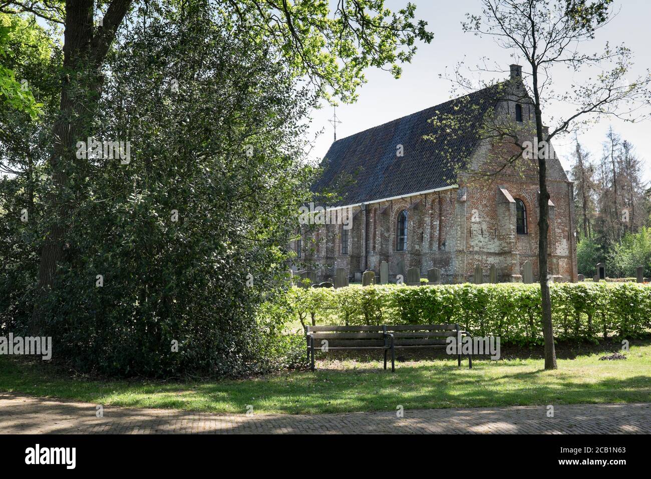 Chiesa tardo gotica di Thomas con una siepe e una panchina di fronte nel piccolo villaggio di Katlijk a Friesland, Paesi Bassi Foto Stock