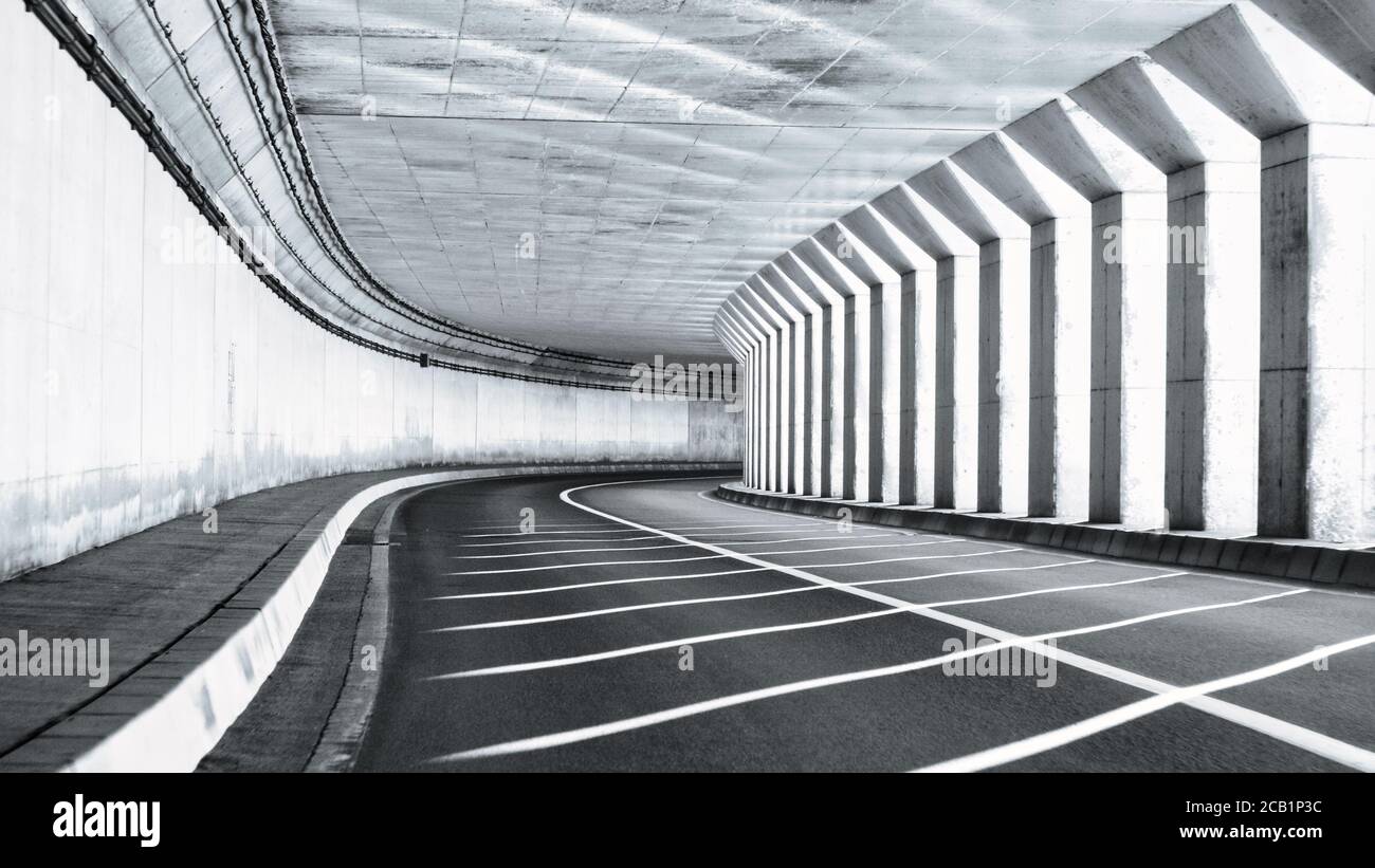 La luce solare filtra tra le colonne in un semittunnel vuoto lungo una strada costiera Foto Stock