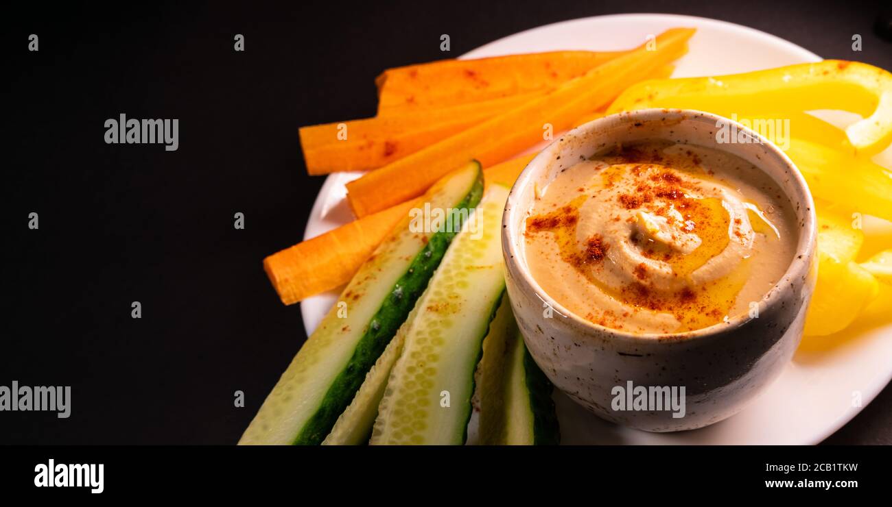 Bagno di hummus e verdure su un piatto, vista dall'alto con spazio per la copia. Pasto vegano sano o antipasto, a base di piante e cibo ricco di vitamine Foto Stock