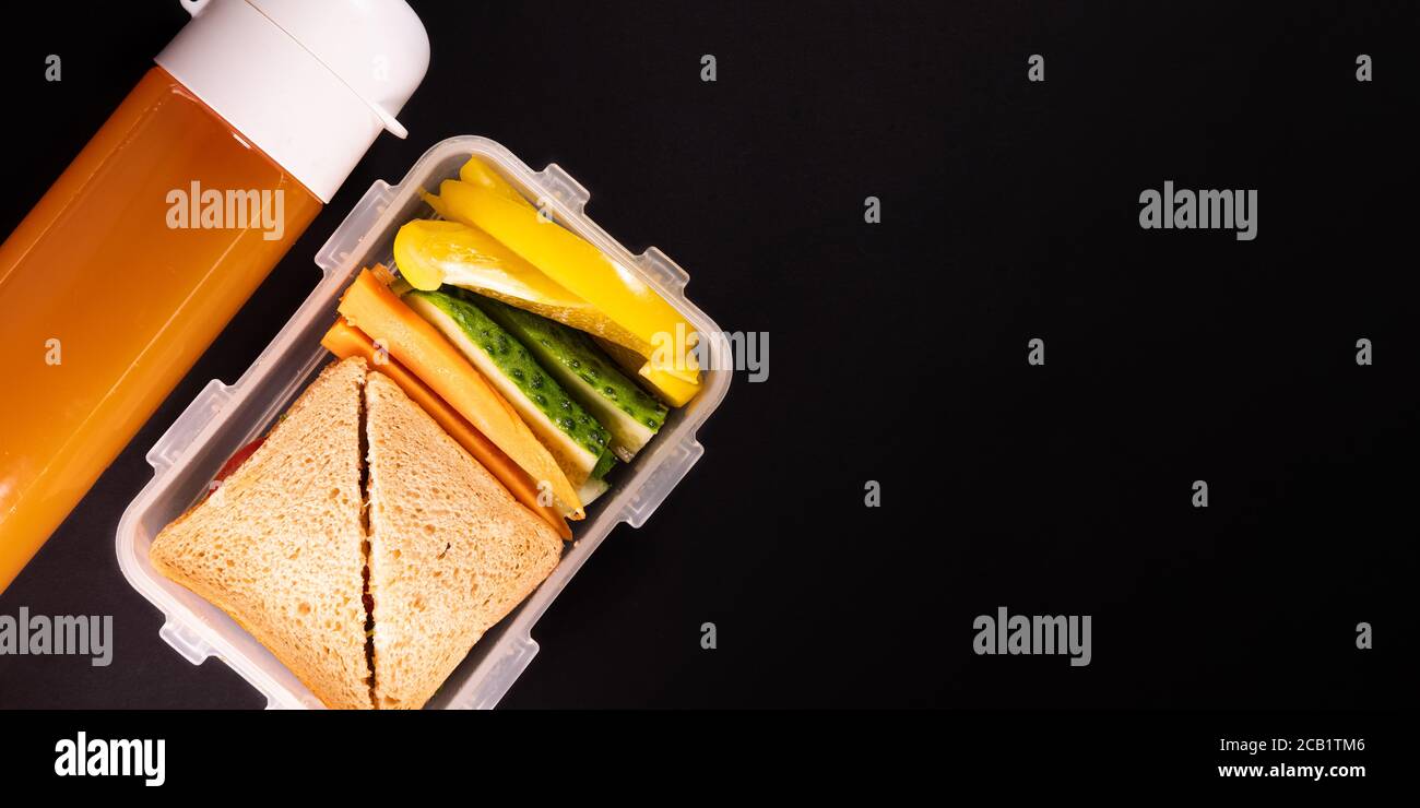 Sandwich di pane e verdure in una scatola per il pranzo accanto a una bottiglia di succo - vista dall'alto e spazio per la copia. Pranzo sano, a base di piante o pranzo vegetariano scuola Foto Stock