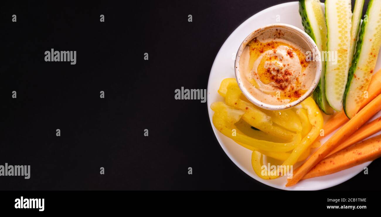 Bagno di hummus e verdure su un piatto, vista dall'alto con spazio per la copia. Pasto vegano sano o antipasto, a base di piante e cibo ricco di vitamine Foto Stock