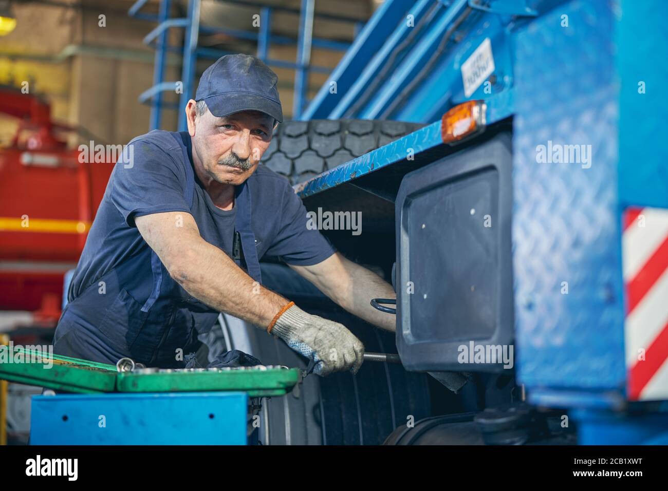 Addetto alla riparazione impegnato che guarda direttamente la fotocamera durante il lavoro Foto Stock