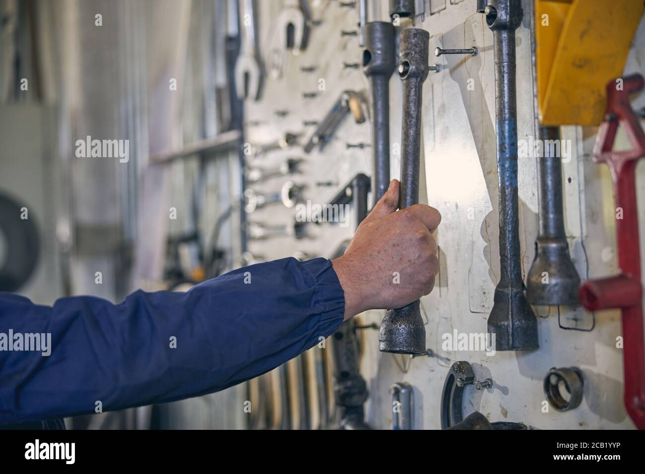 Meccanico forte che prende lo strumento necessario per il lavoro Foto Stock