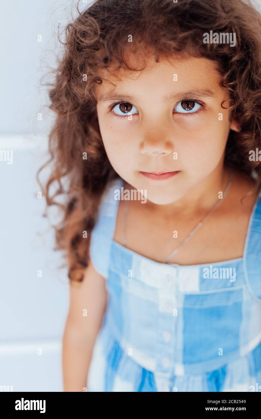 Ritratto di una bella bambina riccia in un blu vestitevi su sfondo bianco  Foto stock - Alamy