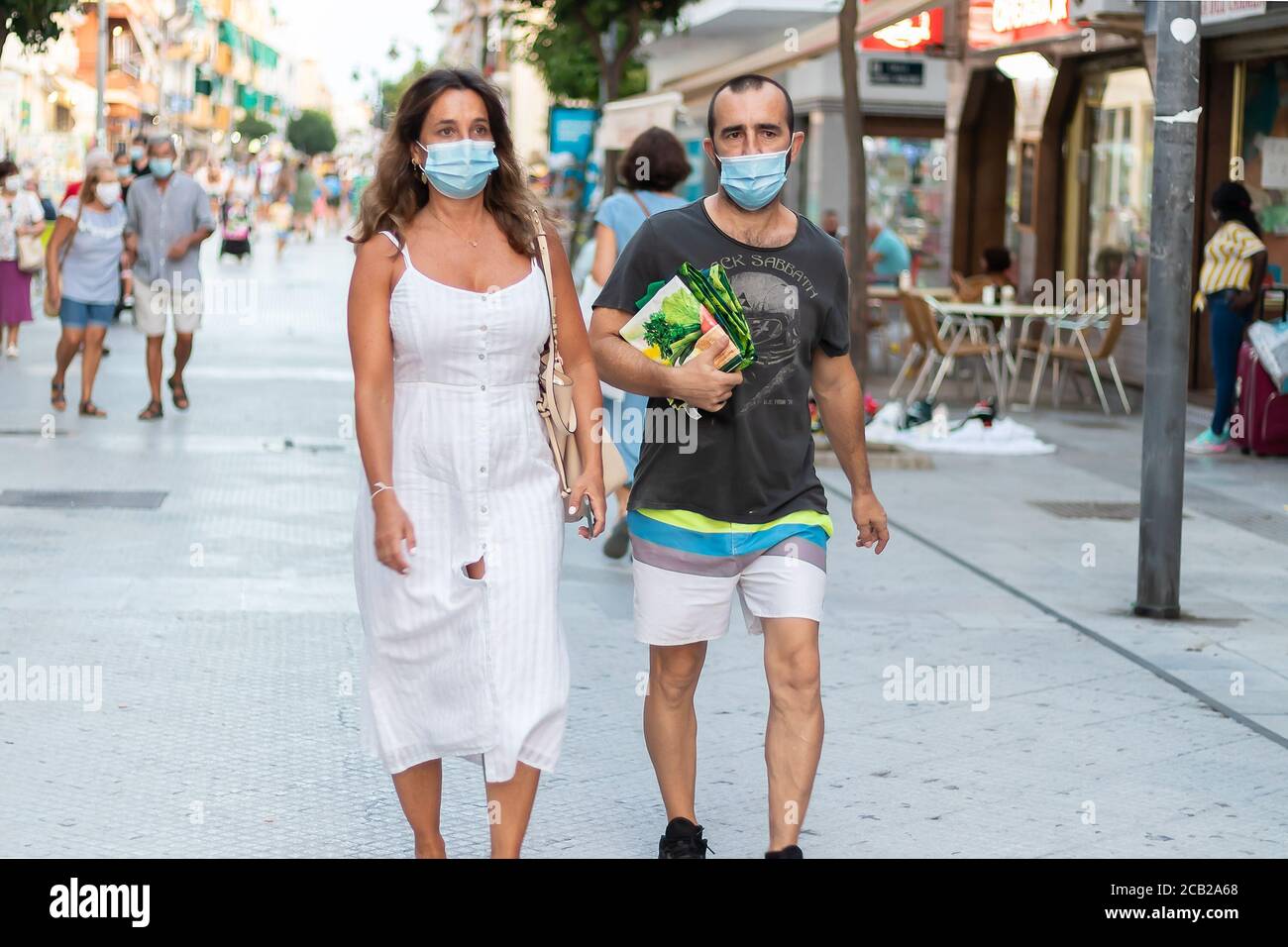 Punta Umbria, Huelva, Spagna - 7 agosto 2020: Coppia camminando per strada 'Calle Anchaa', indossando maschere protettive dovute a covid-19. Nuova normalità in Spagna Foto Stock