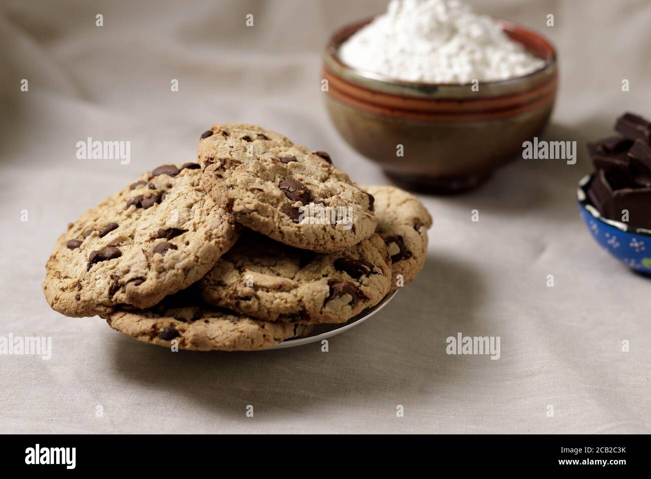Piatto di biscotti fatti in casa al cioccolato con ciotola di fiori in lo sfondo Foto Stock