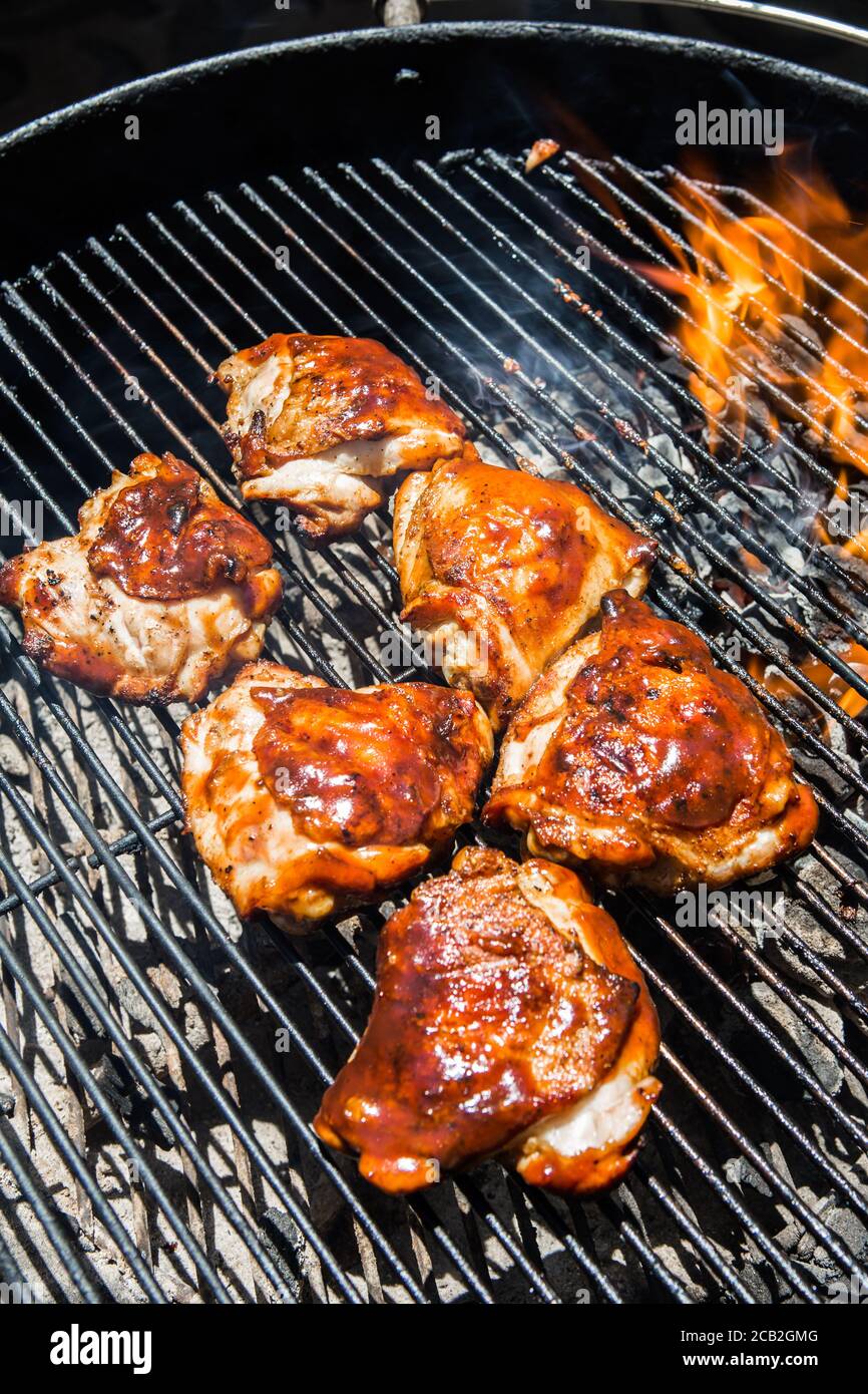 Cosce di pollo marinate smaltate con salsa barbecue cucinate su una griglia  a carbone di giardino Foto stock - Alamy