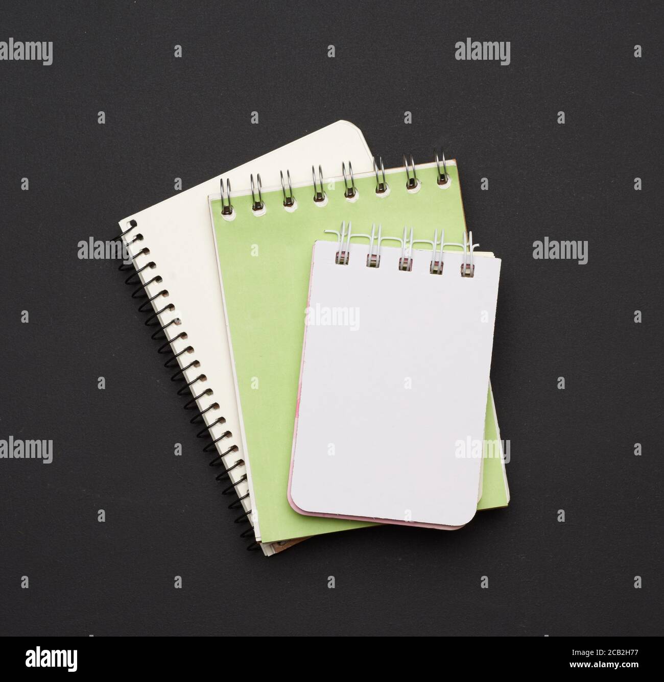 pila di notebook aperti a spirale con fogli bianchi vuoti su sfondo nero, vista dall'alto Foto Stock