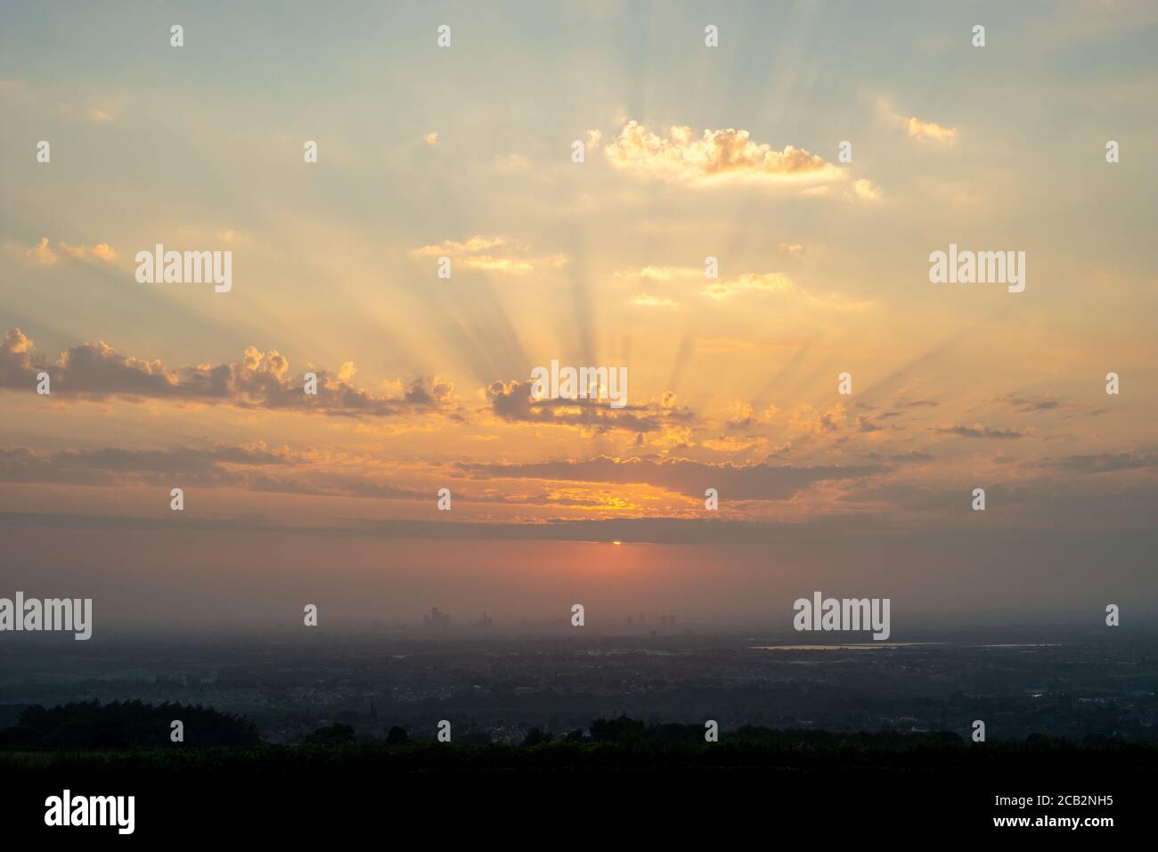 Tramonto sulla città di Manchester in una polverosa serata estiva. La scarsa visibilità dell'aria e le nuvole hanno contribuito a produrre uno spettacolare tramonto rosso arancio profondo. REGNO UNITO Foto Stock
