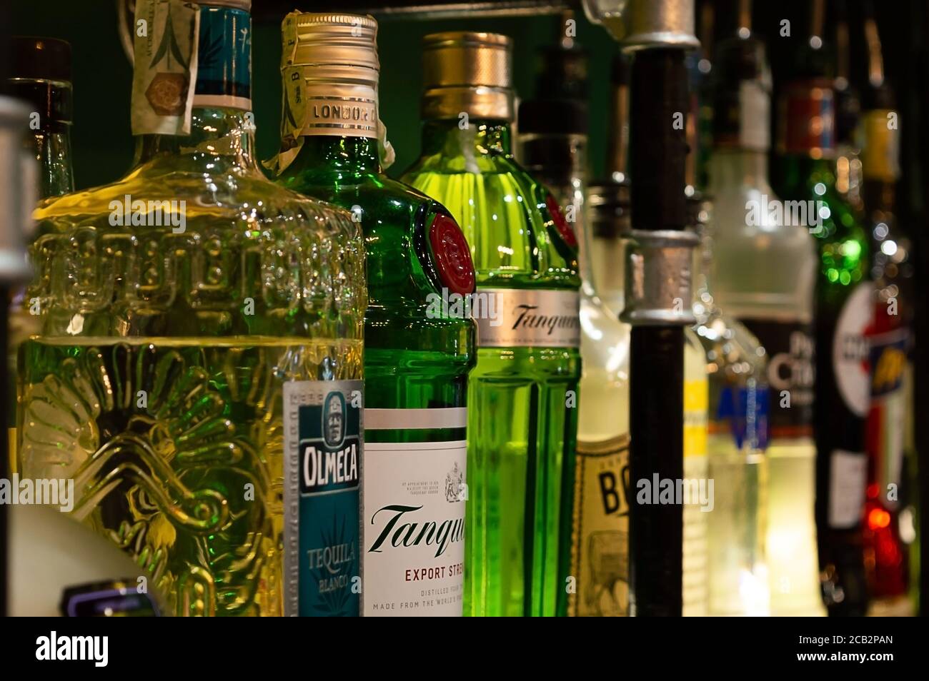 Diverse bottiglie di alcol colorate visualizzate su uno scaffale in a. pub Foto Stock