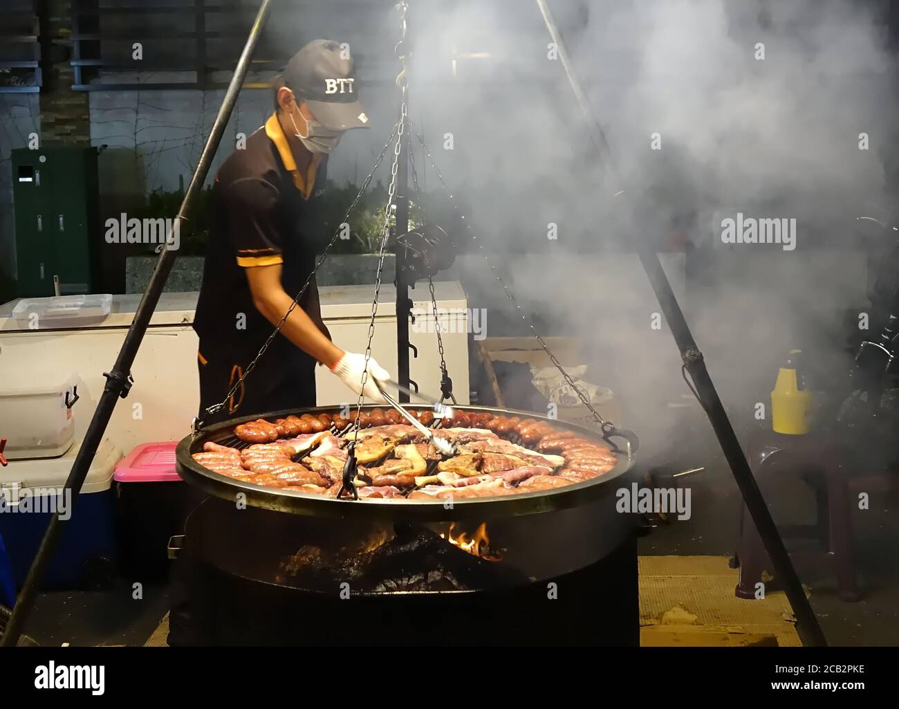 KAOHSIUNG, TAIWAN -- 2 MARZO 2018: Un venditore all'aperto ad un mercato notturno griglia carni fresche di maiale salsicce e carne. Foto Stock