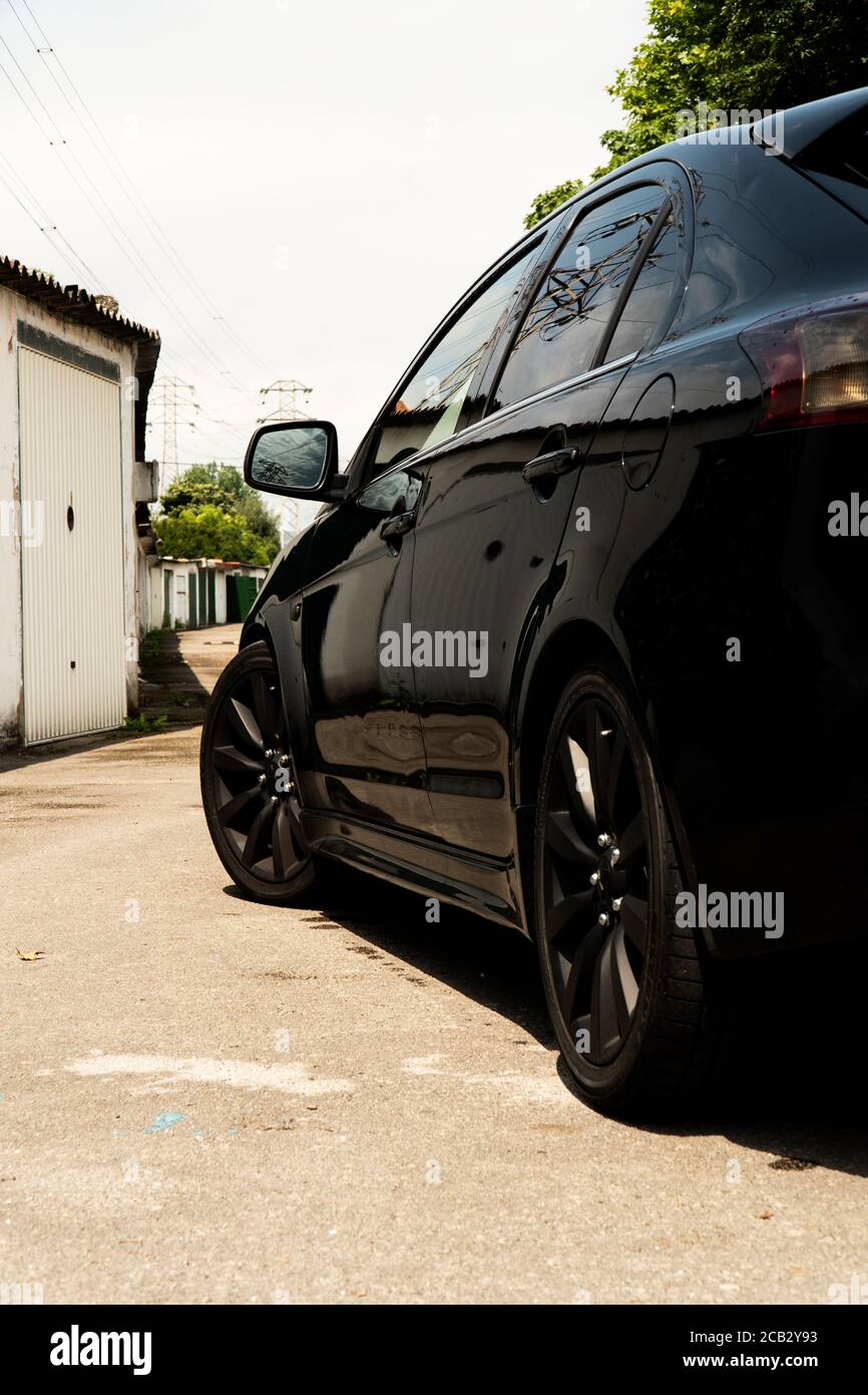 Auto giapponese completamente nera su una strada garage in un giorno di sole Foto Stock