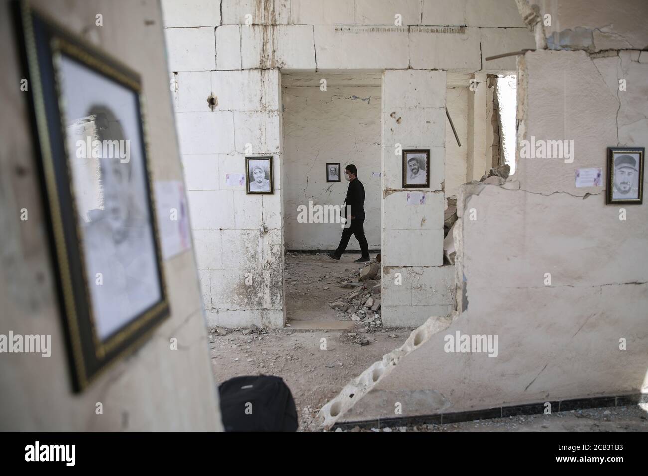 Città di Idlib, Siria. 10 agosto 2020. Un visitatore visita una mostra allestita dall'artista siriano rami Abd al-Haq in una delle case danneggiate in Idlib. I disegni sono di personaggi e figure che sono emersi durante la guerra civile siriana e hanno avuto un'influenza sui media. Credit: ANAS Alkharboutli/dpa/Alamy Live News Foto Stock