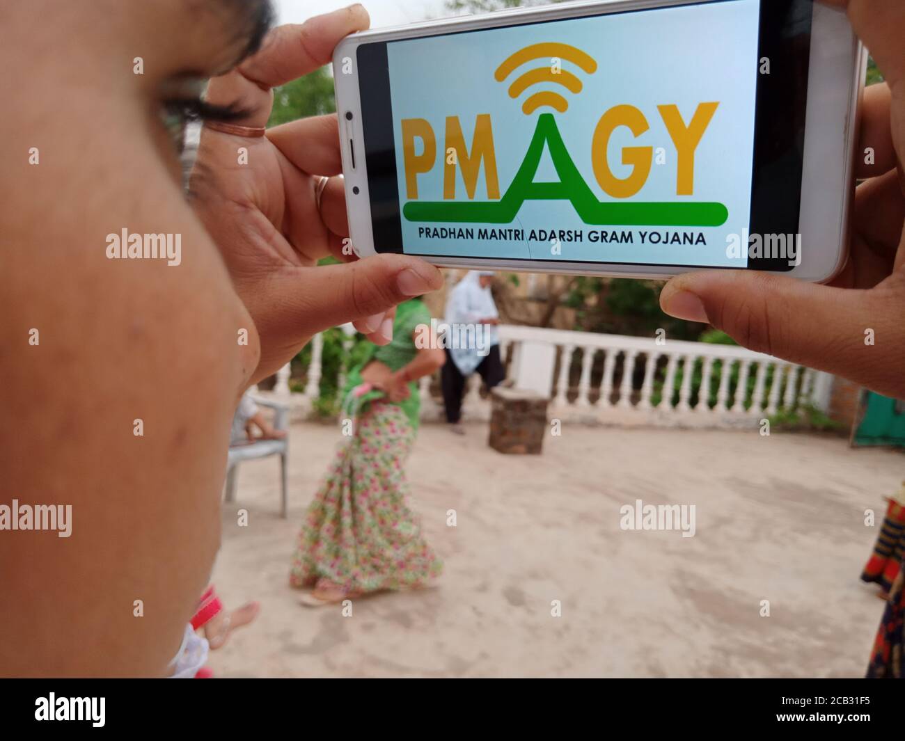 DISTRETTO KATNI, INDIA - 23 MAGGIO 2020: Ragazza che tiene smartphone con pradhan mantri adarsh gram yojana schema su schermo. Partito al governo indiano Foto Stock