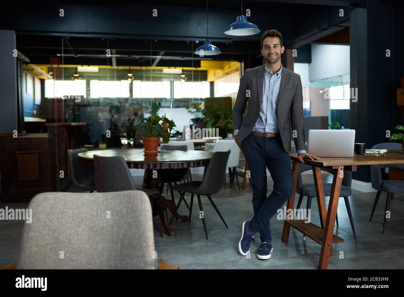 Sorridente giovane uomo d'affari in piedi in un ufficio dopo l'orario di lavoro Foto Stock