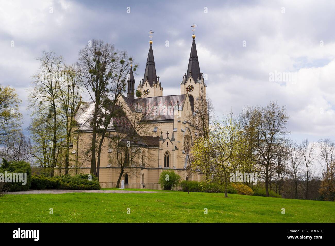Chiesa della Natività della Vergine Maria, Orlova, Slesia, Repubblica Ceca / Czechia - edificio neo-gotico sacrale in un bellissimo parco verde durante la sprin Foto Stock