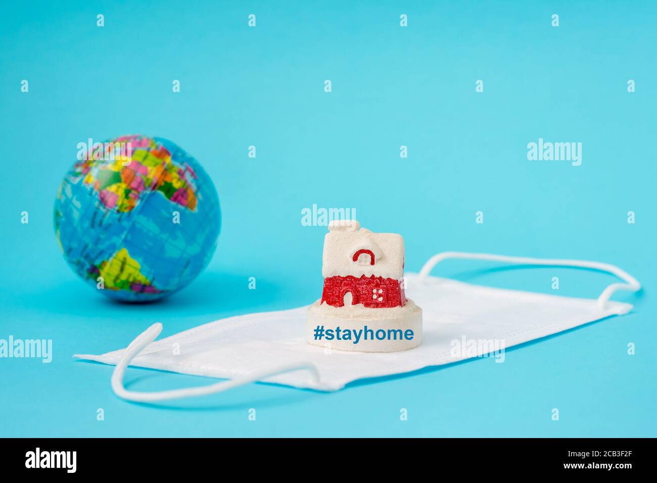 Prevenzione del coronavirus, maschera e globo, rimanere a casa su sfondo azzurro Foto Stock