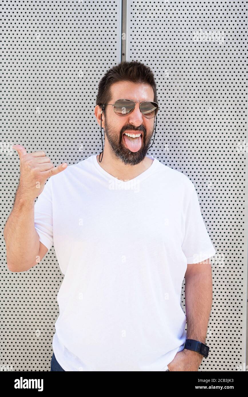 Uomo bearded con gli occhiali da sole che gesturing mentre guardando la macchina fotografica Foto Stock