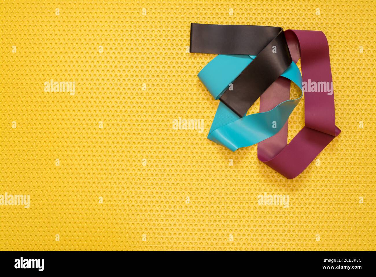 Vista dall'alto di una fascia Pilates sul tappetino giallo. Sport a casa, yoga e Pilates pratica Foto Stock