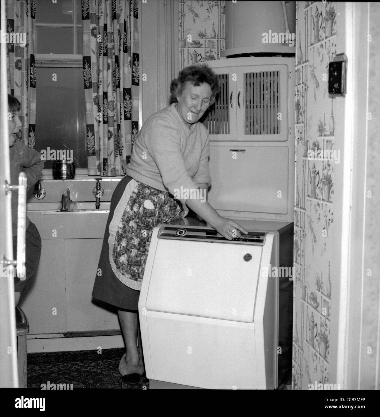 Una donna non vedente degli anni '50 non lascia la sua cecità influisca sulla sua vita come lei usa la lavatrice hoovermatic che ha controlli in braille Foto Stock