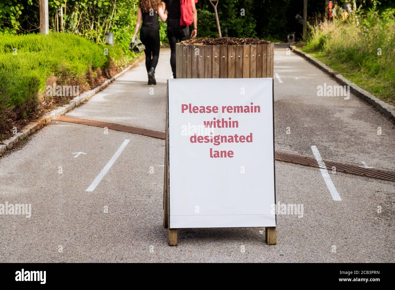 Messaggio che indica di mantenere una distanza di sicurezza e di utilizzare diverse direzioni linee di percorso per camminare. Nuove misure normali di allontanamento sociale nei luoghi pubblici d Foto Stock