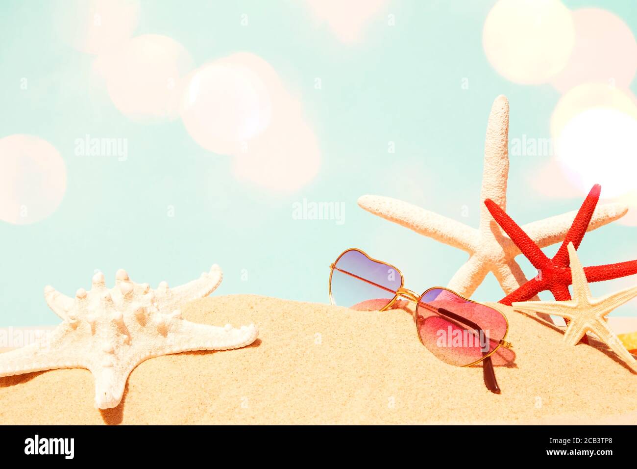 Occhiali da sole con stelle marine sulla spiaggia di sabbia Foto Stock
