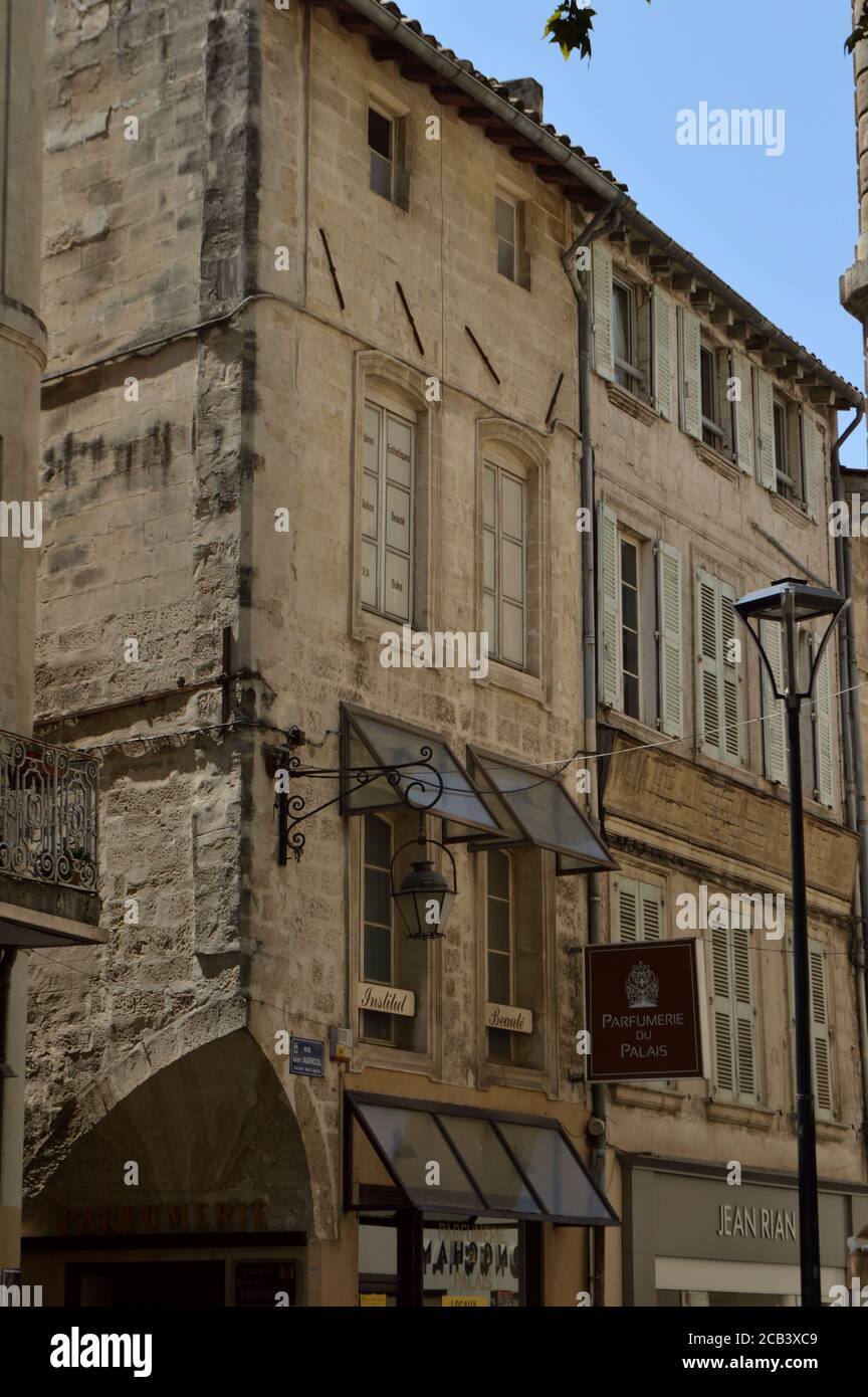 Antico edificio d'angolo in pietra con lampade e insegne di negozi ad Avignone, Vaucluse, Provenza, Francia, 29 luglio 2020 Foto Stock