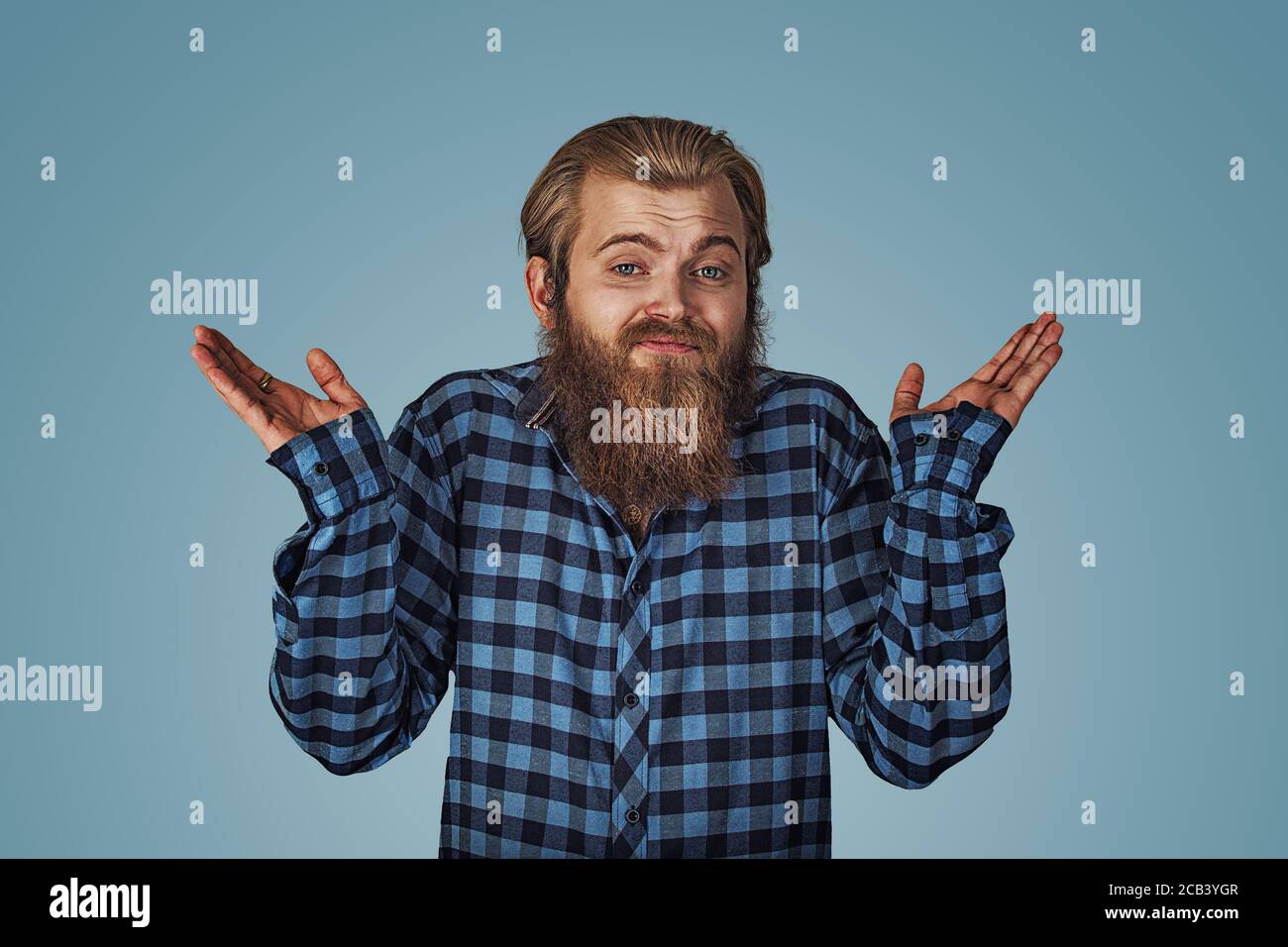 Ignoranza e arroganza. Giovane uomo che si fa carico di spalle che cosa. Hipster maschio con barba in camicia a scacchi blu plaid isolato su una borchia blu Foto Stock