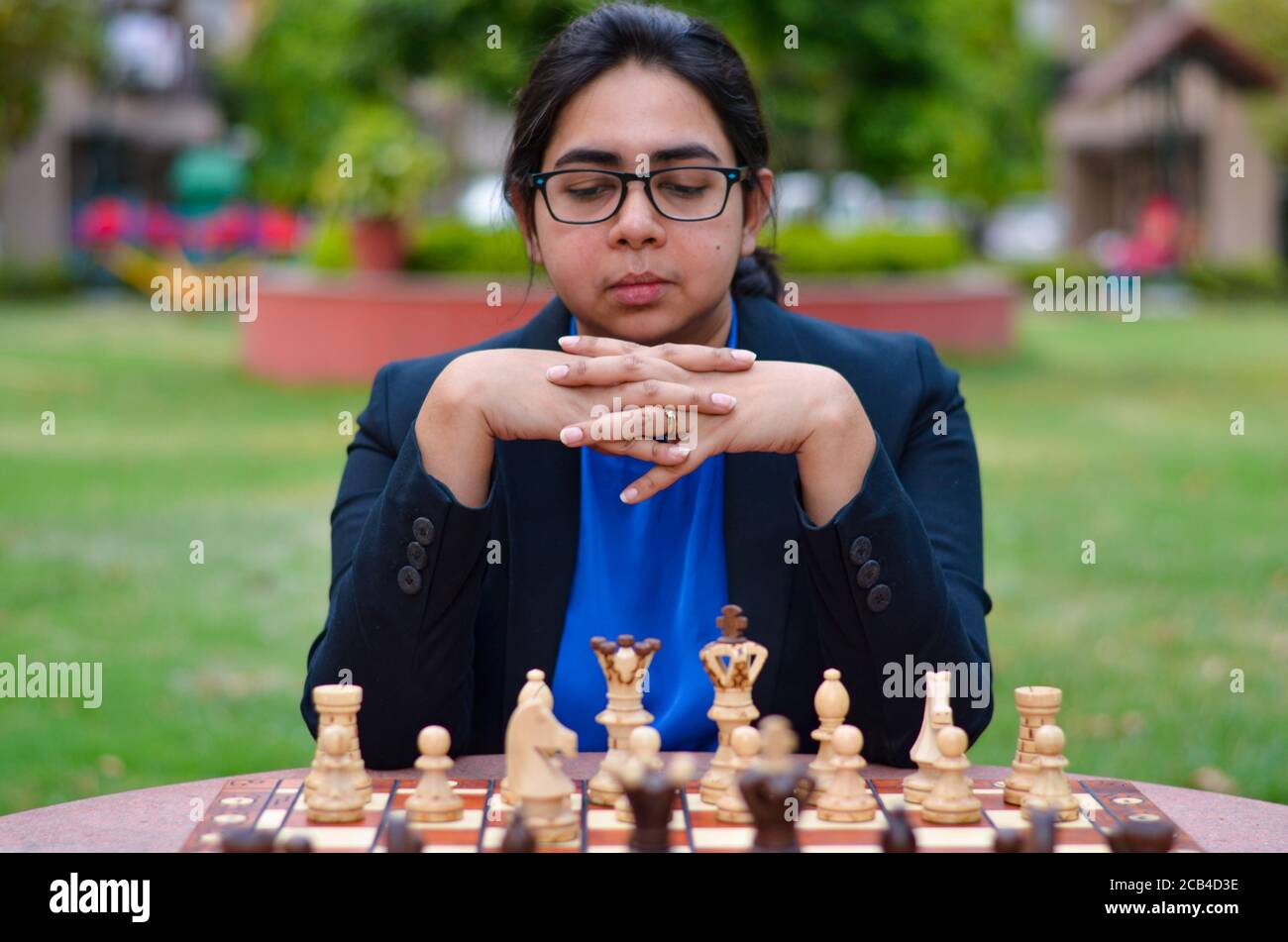 Una ragazza indiana che gioca a scacchi in attesa che l'avversario giochi e che pensa ansiosamente alla sua prossima mossa. Concetto - idea, strategia Foto Stock