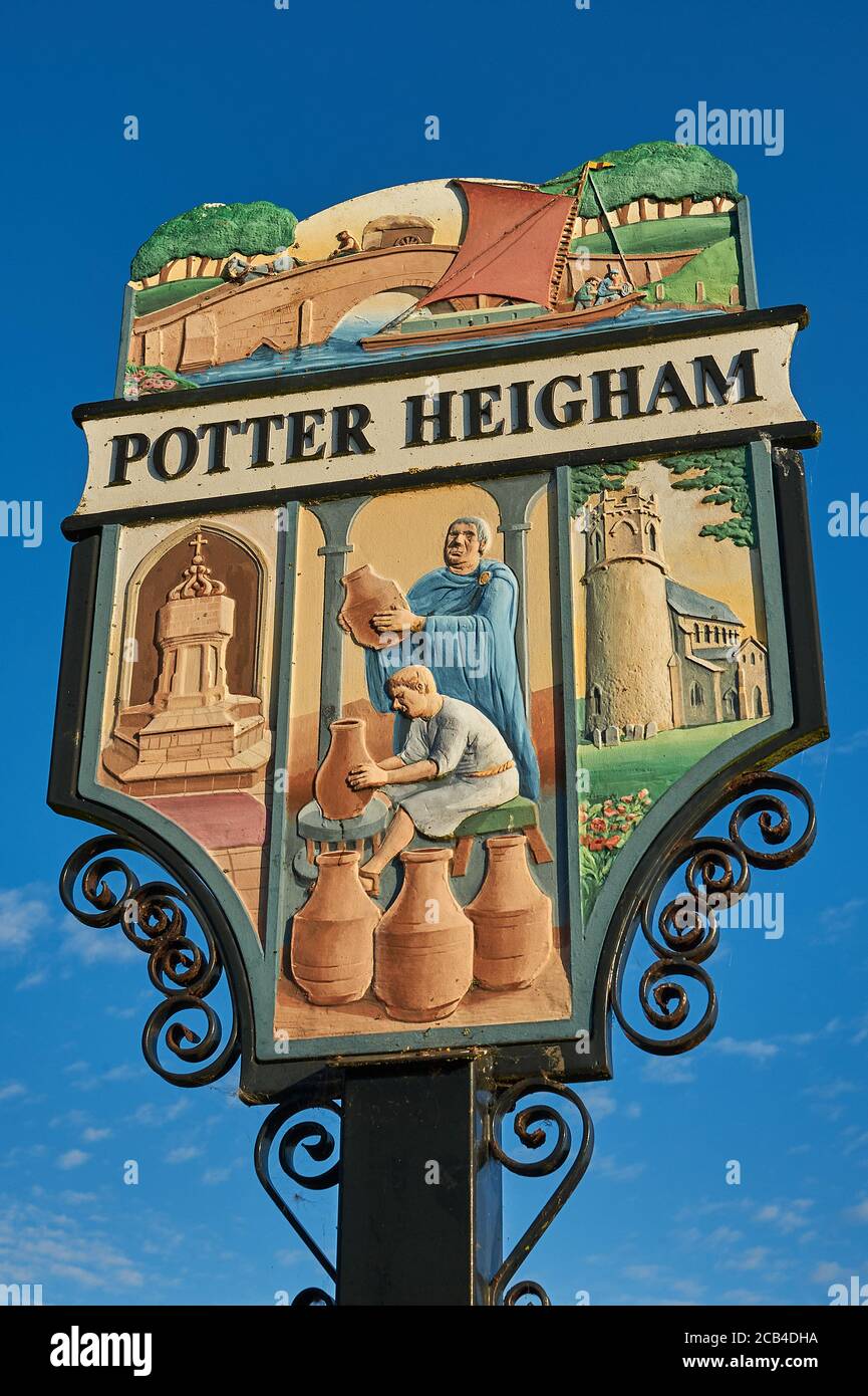 Segno ornato villaggio per Potter Heigham, Norfolk, contro un cielo blu Foto Stock