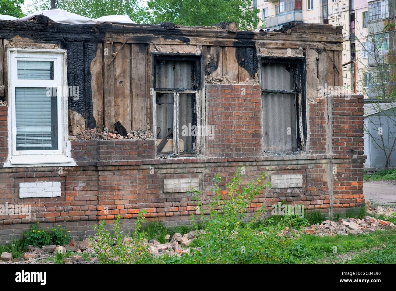 Edificio parzialmente bruciato senza tetto. Una vecchia casa a un piano dopo il fuoco. Un vecchio edificio danneggiato da un forte incendio, finestre bruciate e coll Foto Stock