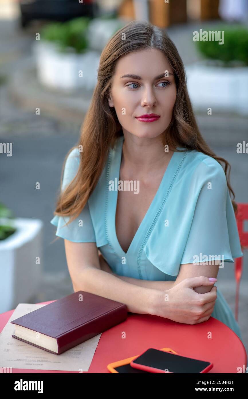 Romantica ragazza carina seduta in caffè, riposando i gomiti sul tavolo Foto Stock