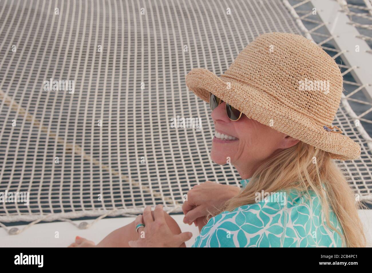 Felice all'aperto. donna matura attiva di 60 anni in cappello di paglia su una barca che sorride con un grande sorriso e denti bianchi. Buon pensionamento. Versione del modello. Foto Stock Felice all'aperto. donna matura attiva di 60 anni in cappello di paglia su una barca che sorride con un grande sorriso e denti bianchi. Buon pensionamento. Versione del modello. Foto Stock